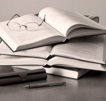 opened books pen and glasses on sepia background